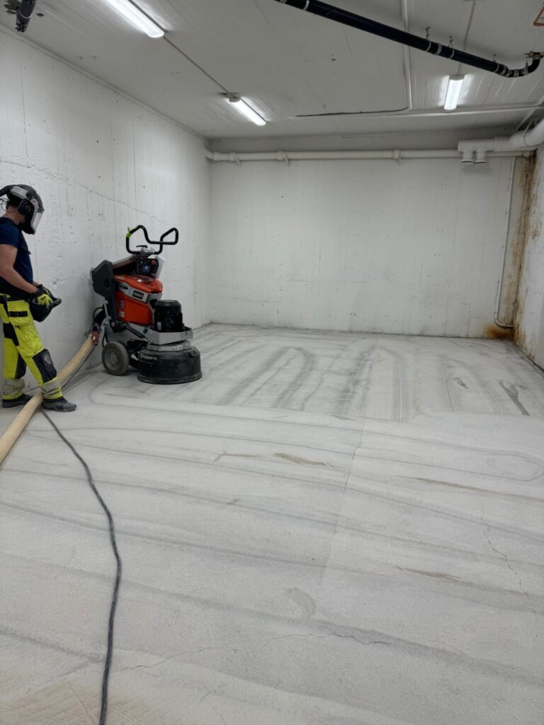 Slipning av betonggolv i källargång inför polering